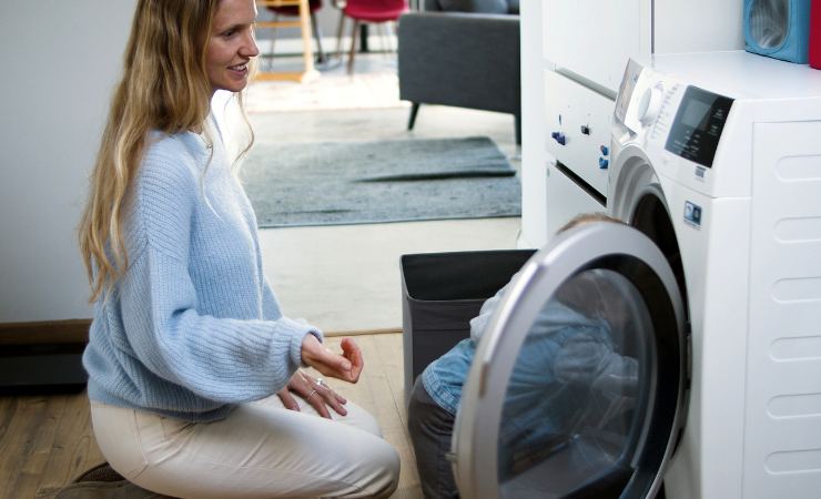 donna davanti alla lavatrice con bucato